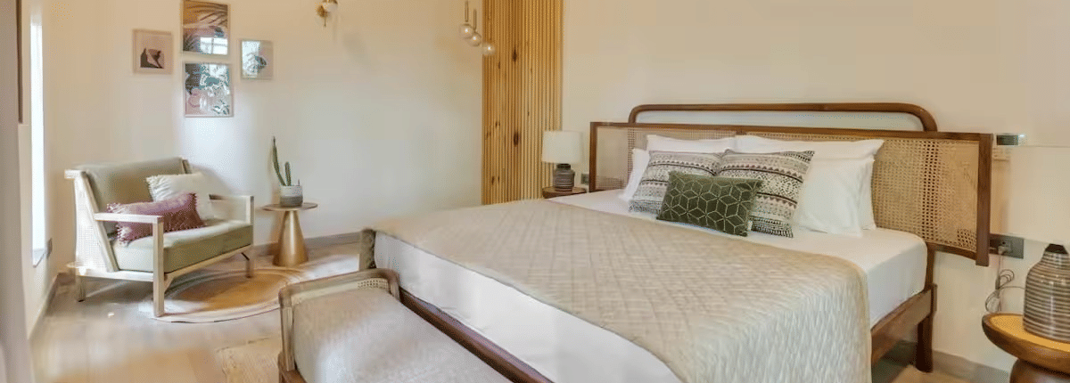 Spacious room with a neatly made bed, bedside table, seating at the foot of the bed, and a cushioned sofa at Lime Tree Villa with Private Pool | Luxury Stay in Goa.